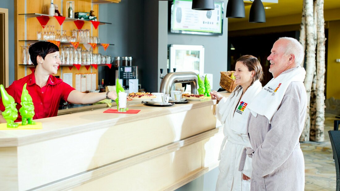 Personen werden von Servicekraft an der Bar bedient.